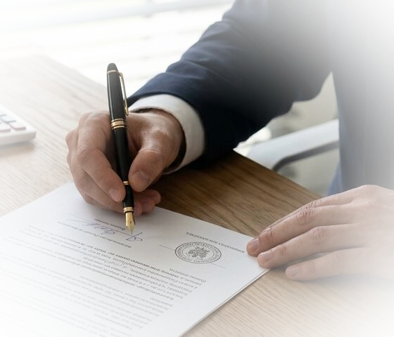 Podpisywanie aktu notarialnego &ndash; zbliżenie na dłoń i pióro